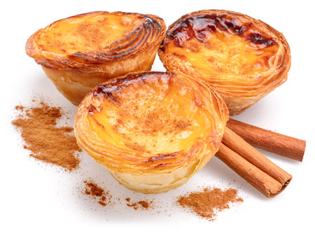 Pastel de nata tarts and cinnamon sticks isolated on white background.