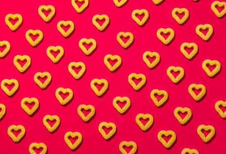 Small heart-shaped cookies on a red background. A beautiful background for Valentine's Day.の写真素材