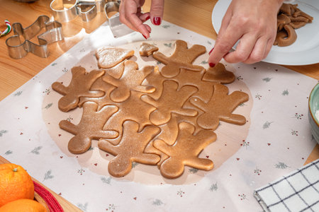 Making Christmas cookies - gingerbread men, woman is cutting out the cookies with molds.の写真素材