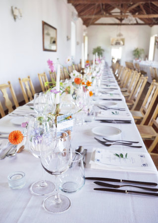 Banquet table in rustic European style. White tablecloth and empty glasses and plates.の写真素材