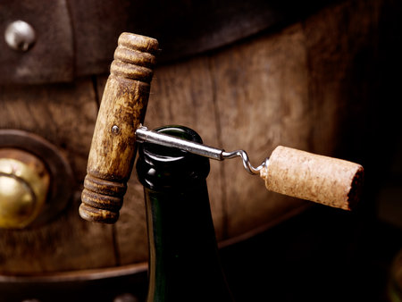 Opening a bottle of wine with a corkscrew. Blurred wine cask at the background. Top view.の写真素材
