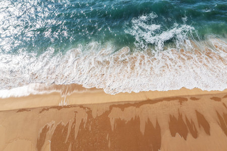 Azure ocean water and ocean foam covering beautiful long sandy beach, aerial drone view. Beautiful nature background.の写真素材