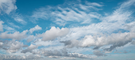 Sky panorama filled with a variety of clouds, from fluffy cumulus to wispy cirrus, stretches across...