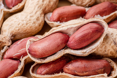 Pile of whole and cracked peanuts close up. Food background.