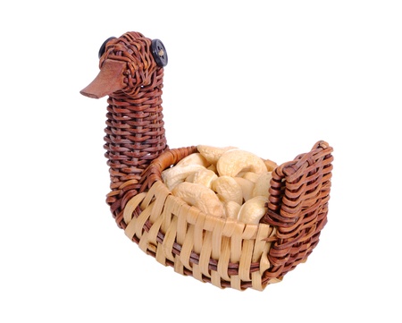 Cashew nuts in a wicker bowl in the form of a duck isolated on whiteの写真素材