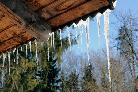 Icicles on a roof of a wooden shed in the springの写真素材