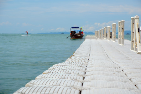Pier against the sea, the boat and mountains, focus on foregroundの写真素材