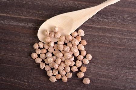 A handful of chick-pea and spoon on a wooden backgroundの写真素材