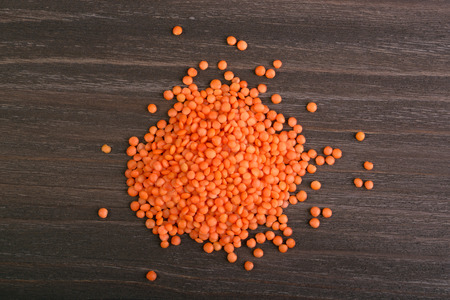 Handful of red lentils on a wooden backgroundの写真素材