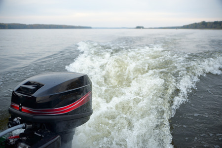 Motor boat trail in calm river waters on a autumn dayの写真素材