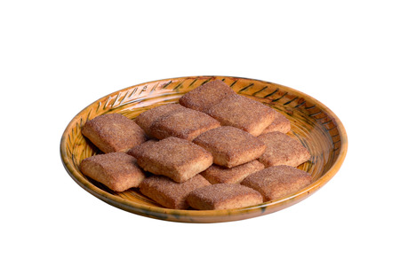 A cookie with cinnamon lies on a golden plate, isolated on whiteの写真素材