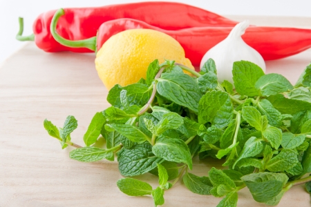 Fresh mint leaves, lemon, bell pepper and garlic for salad or salsa on wooden board  selective focus, shallow dofの写真素材