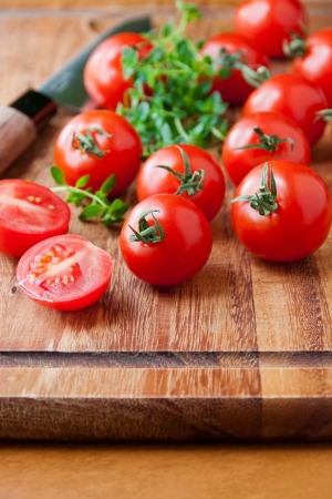 Tomatoes, thyme herb and knife on wooden cutting board  selective focus, shallow dofの写真素材