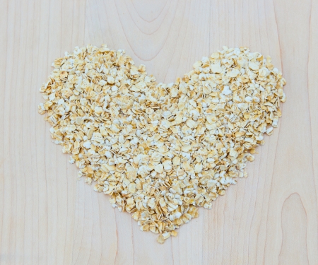 Whole grain oats in heart shape on wooden board, healthy food の写真素材
