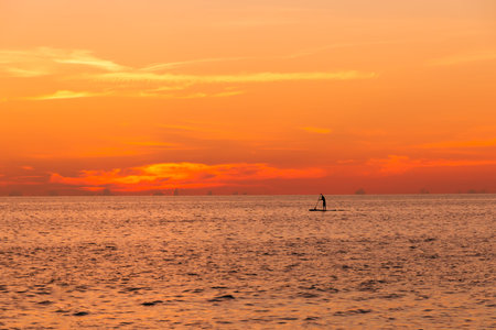 Man on paddle board at ocean sunset
