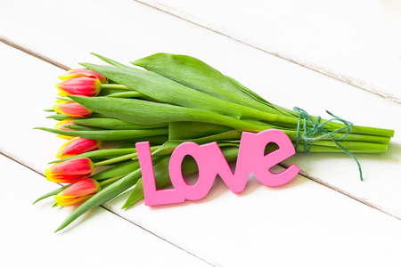 Bouquet of yellow red tulips on  wooden background with Love word.の写真素材