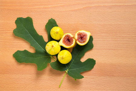 Yellow tiger figs with leaves on wooden background.