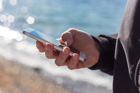 attractive guy is holding a smart phone and using itの写真素材