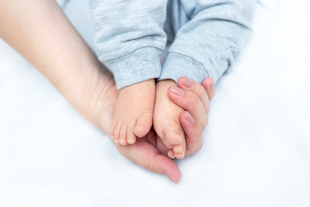 mother is holding feet of her newborn baby in her handsの写真素材