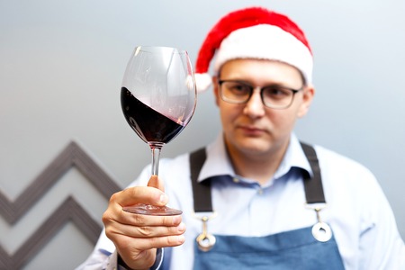 a man is drinking wine in a santa hat on a new year partyの写真素材