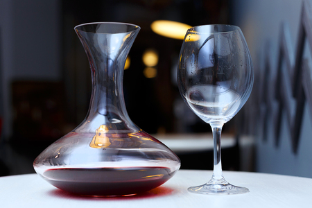 Decanter with red wine and a glass on a white tableの写真素材