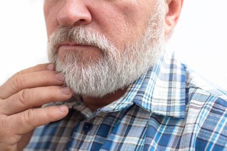 Getting perfect shape. Close-up side view of old bearded man getting beard haircutの写真素材