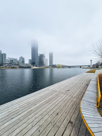 Vienna, Austria - January 2, 2025: urban waterfront with modern cityscape and wooden platform