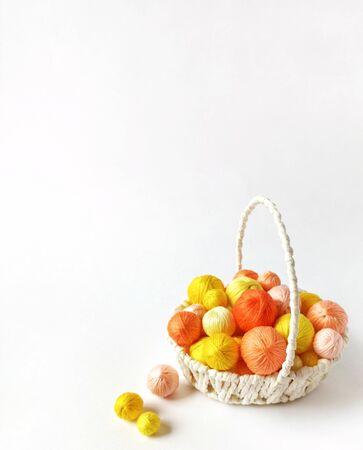 White basket with orange and yellow yarn for knitting. Yellow threads for needlework. Balls of yarn for hand knitting.の写真素材