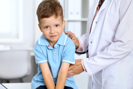 Happy little boy having fun while is being examine by doctor with stethoscope. Health care, insurance and help conceptの写真素材
