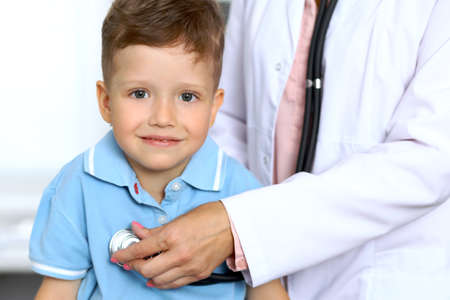 Happy little boy having fun while is being examine by doctor with stethoscopeの写真素材