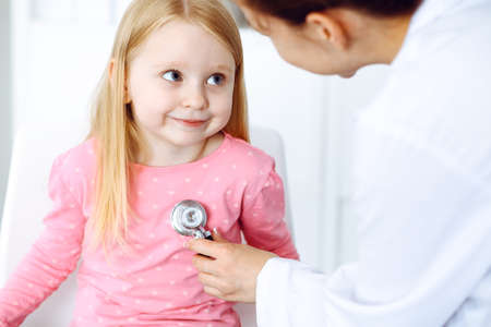 Happy smiling child patient at usual medical inspection. Doctor and little girl in clinic. Medicine, healthcare conceptsの写真素材