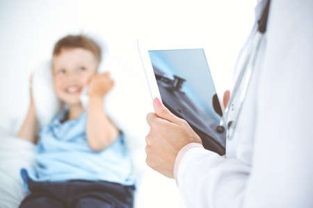 Happy smiling male kid-patient at usual medical inspection. Doctor and young boy in the clinic. Medicine conceptsの写真素材