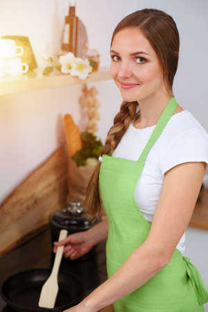 An attractive young woman ready to cook a new recipe for a delicious salad mix while standing in sunny kitchenの写真素材