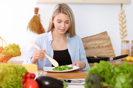 Two women friends choose the recipe and ingredients for a delicious meal while sitting in sunny kitchen. Vegetarian conceptの写真素材