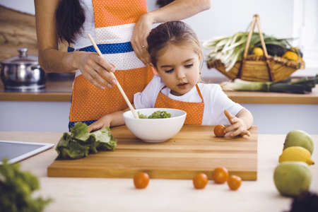 Happy woman and her daughter making healthy vegan salad and snacks for family feasting. Christmas, New year, Thanksgiving, Anniversary, Mothers Day. Healthy meal cooking conceptの写真素材
