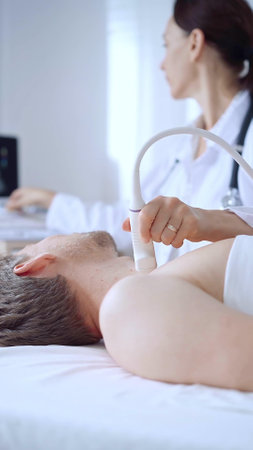 Doctor woman performing neck ultrasound exam on male patient. Medicine service conceptの写真素材