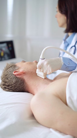 Doctor performing neck ultrasound exam on male patient