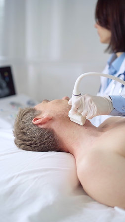 Doctor performing neck ultrasound exam on male patient