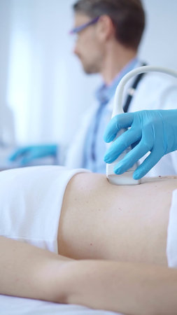 Doctor man wearing a blue protective gloves using an ultrasound machine on a female patient examining internal organs. Medicine conceptの写真素材