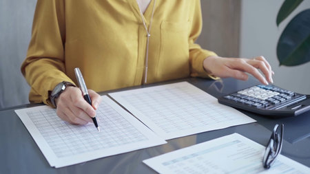 Professional business woman in yellow blouse is working on financial reports. Close-up of a womans...