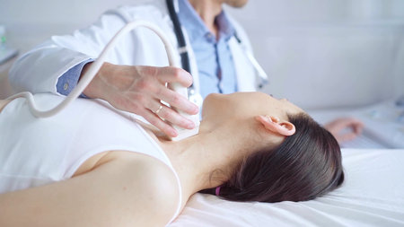 Doctor man is using ultrasound equipment on neck of female patient lying down for a medical...