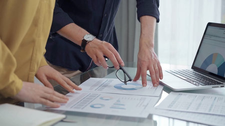 Business people, professionals analyzing financial charts and data on a desk while standing and...