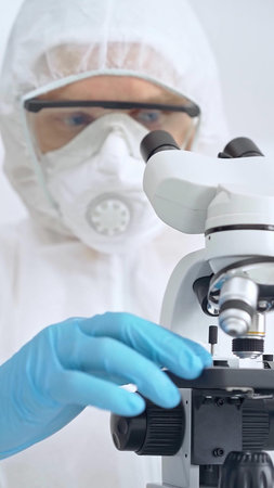 Scientist in ppe analyzing samples and analyzing samples with a microscope in a laboratory setting,...