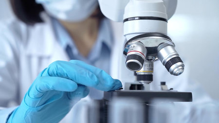 Scientist using microscope in laboratory. Close-up of a researchers hands adjusting a modern...