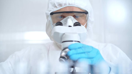Scientist in ppe analyzing samples using a microscope in a laboratory setting. Close-up of a focused...