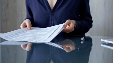 Businessperson woman in dark blue blouse analyzing document at glass desk. Close-up of a...