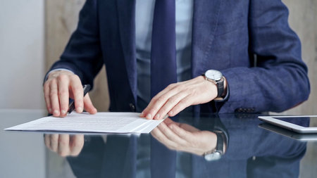 Businessman reviewing documents at office desk. Close-up of a professional mans hands examining...