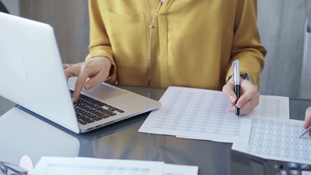 Businesswoman or professional auditor is analyzing data on laptop. Close-up of female bookkeeper...