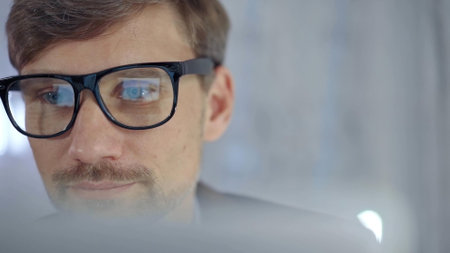 Businessman with glasses looking intently obscured partially by a translucent surface of laptop. Business conceptの写真素材