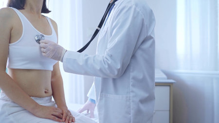 Doctor and patient. Physician wearing white medical gloves is using stethoscope examining woman in clinic. Medicine conceptの写真素材